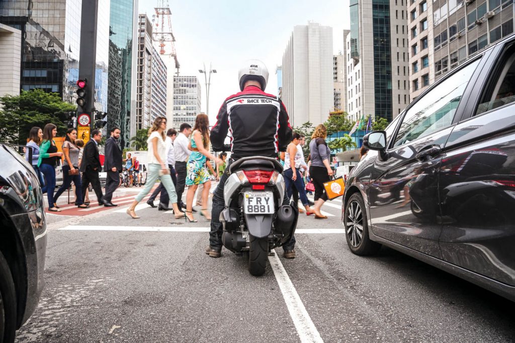 Motociclista aguardando em cruzamento da avenida Paulista, em São Paulo