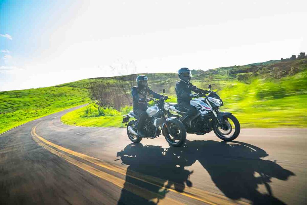 imagem dos pilotos na estrada com a Royal Enfield Guerrilla 450 e Bajaj Dominar NS400Z